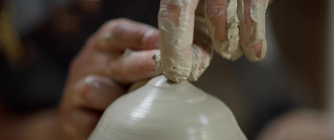 A man sculpts a vase on a pottery wheel
