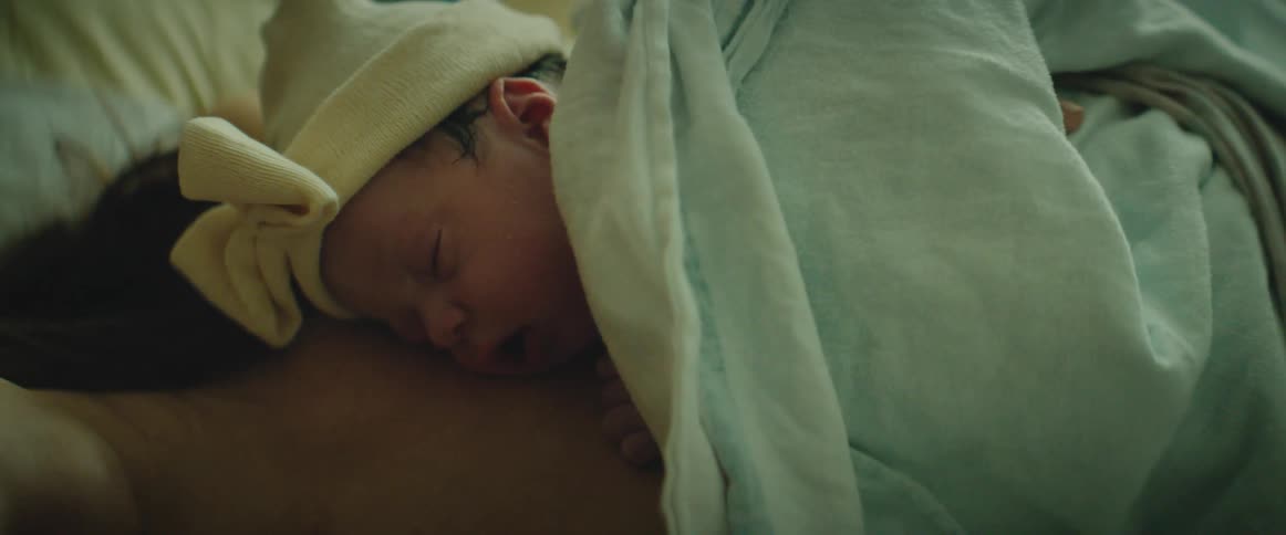 A newborn is sleeping on top of his mother