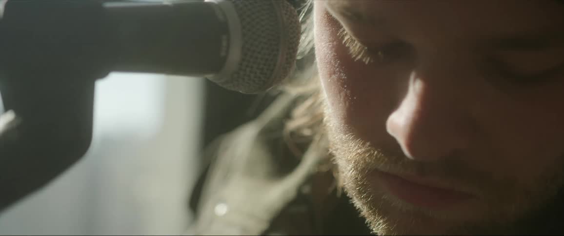 Male singer with beard and mustache sings into microphone