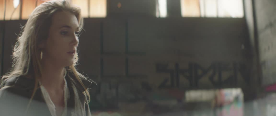 Blonde model looking around an abandoned warehouse next to a photographer