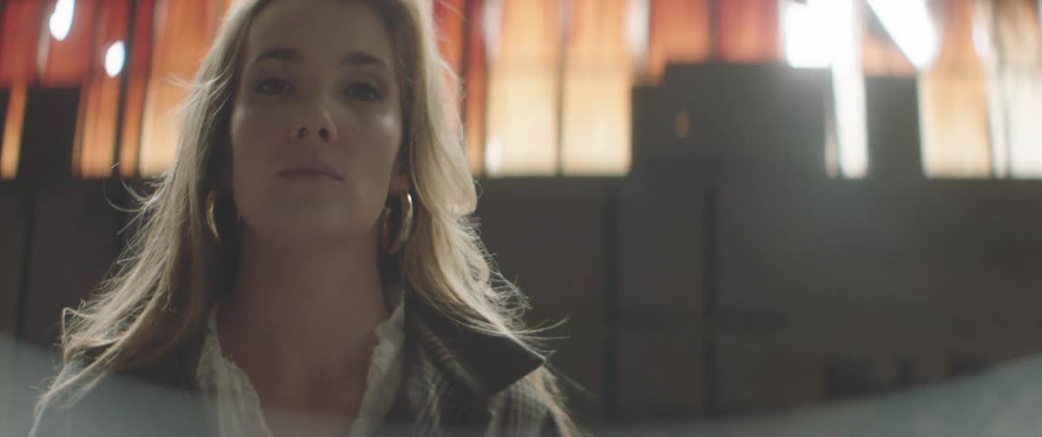A woman is looking at the camera and standing indoors