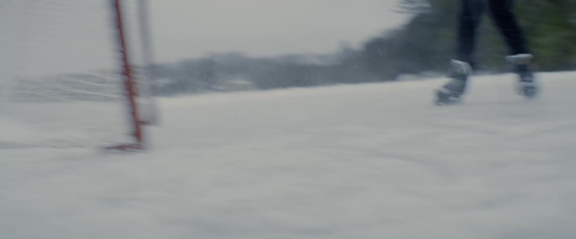 Man riding ice skates practices shots at the goal on a frozen lake