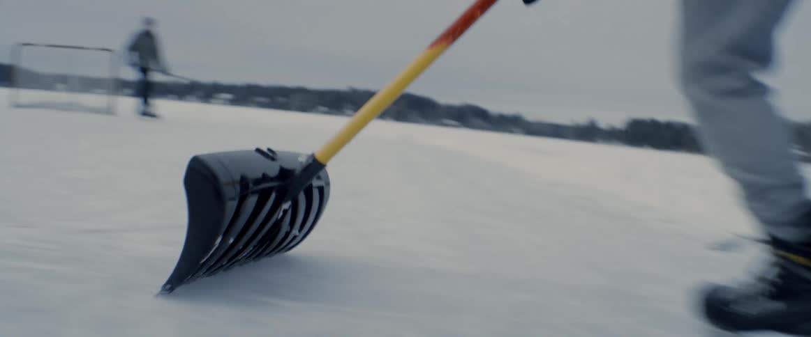 A person pushes a shovel while using ice skates