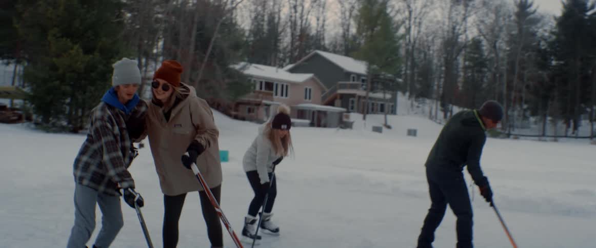 A woman playfully shoves a kid during an ice hockey game on a frozen lake