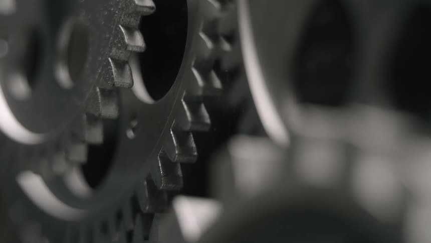 Silver metallic gears rotate as their teeth engage