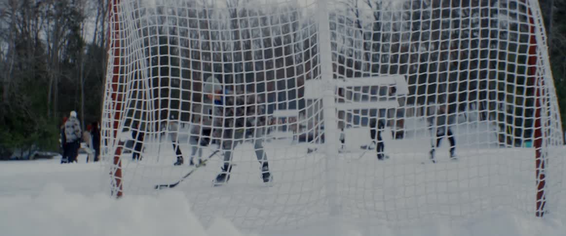People practice ice hockey on frozen area near houses