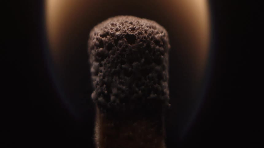 A flame ignites a wooden match and it is on fire