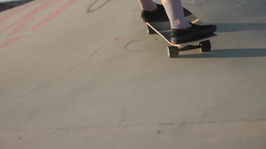 A girl skateboards at a skateboard park as two boys watch