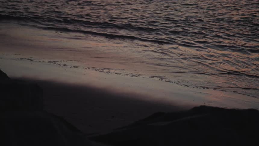 The tide slowly washes into an empty beach