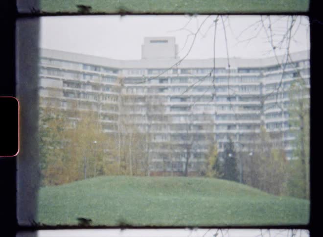 Small grassy hill in front of an apartment building caught on vintage film