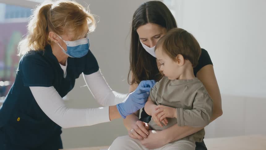 Mother hugging her son as a nurse sterilizes his arm to apply a vaccine