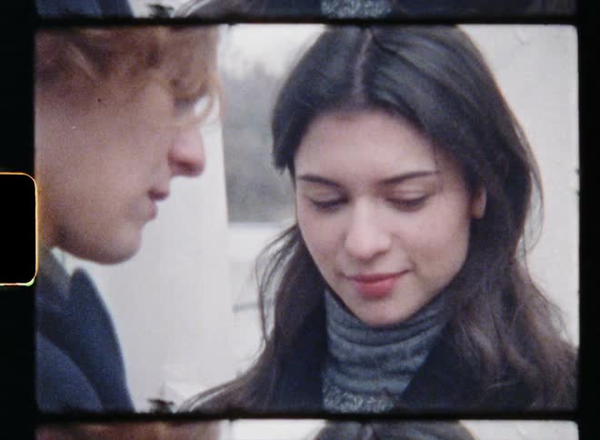 A vintage film of a teenage boy and girl standing together and looking at one another