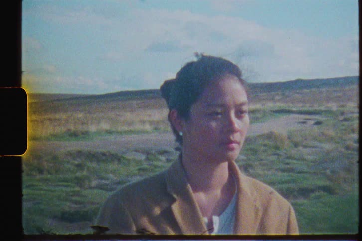 A woman stands in a wide open field