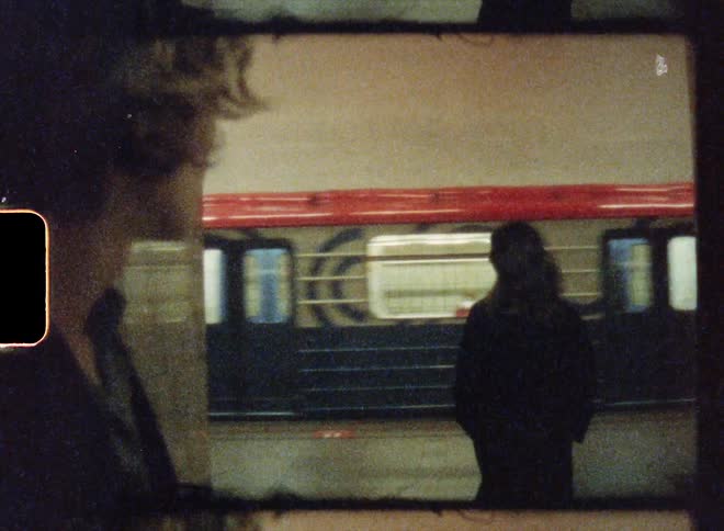 A man and woman are looking at each other and she turns and walks toward the passing train