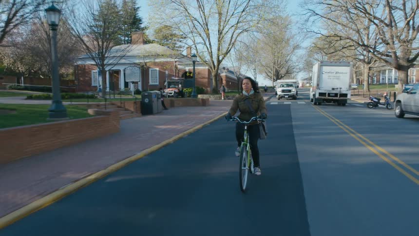 Woman riding a bicycle on a small road town at morning