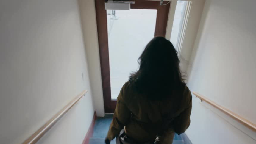Woman walking down a flight of stairs to the outdoors