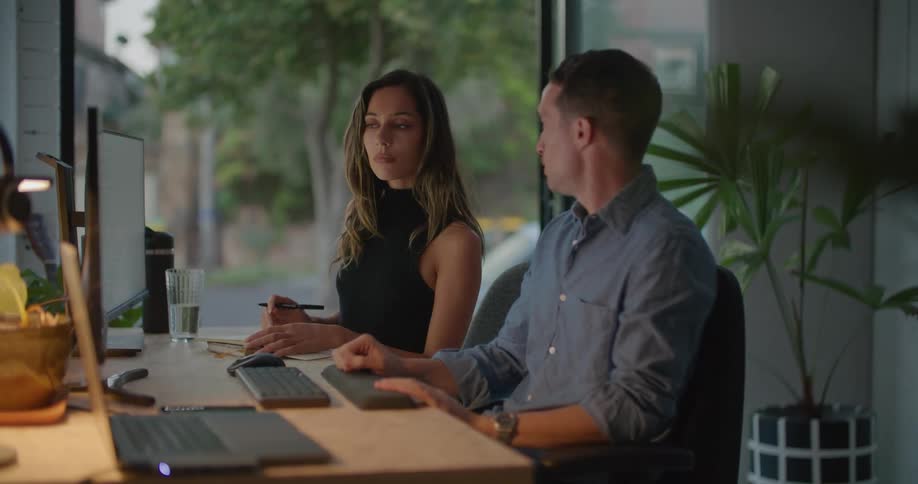 A woman takes notes as she sits next to her coworker as they collaborate
