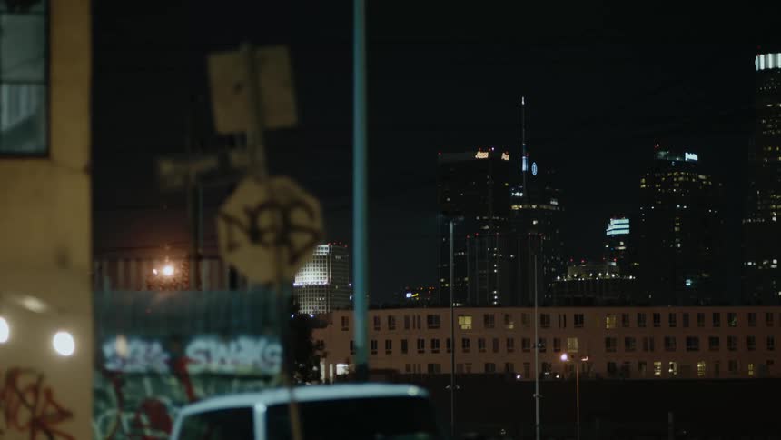 A city street at night with graffiti on buildings and fence