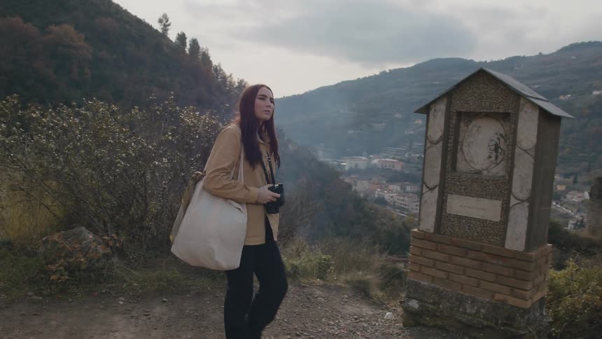 A woman walks on the mountain overlooking the town