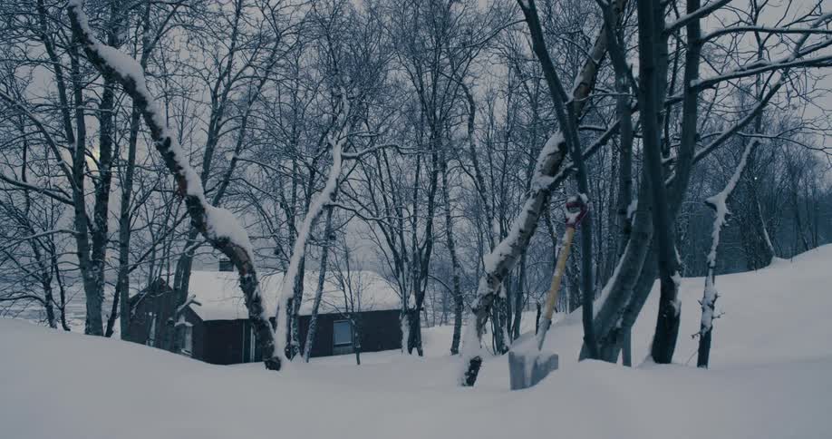 A solitary cabin is located in a remote snowy area in the midst of winter