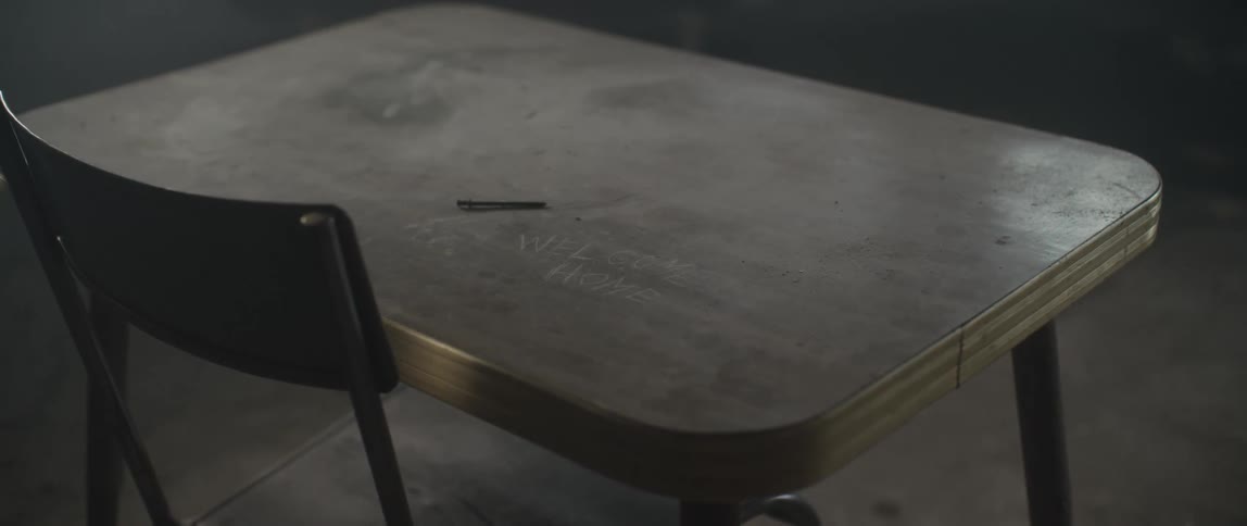 A small dirty table with welcome home scratched into the surface