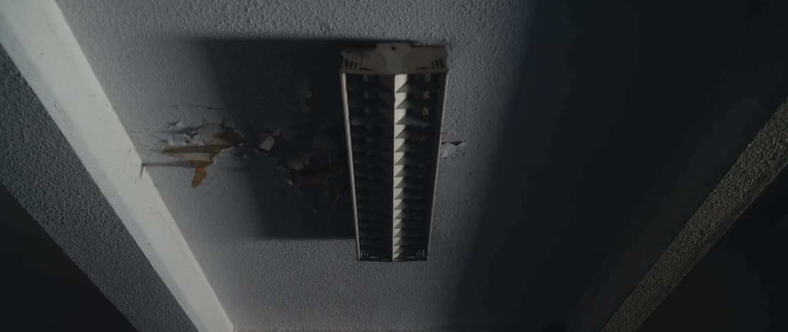 A damaged ceiling next to a light fixture in a home