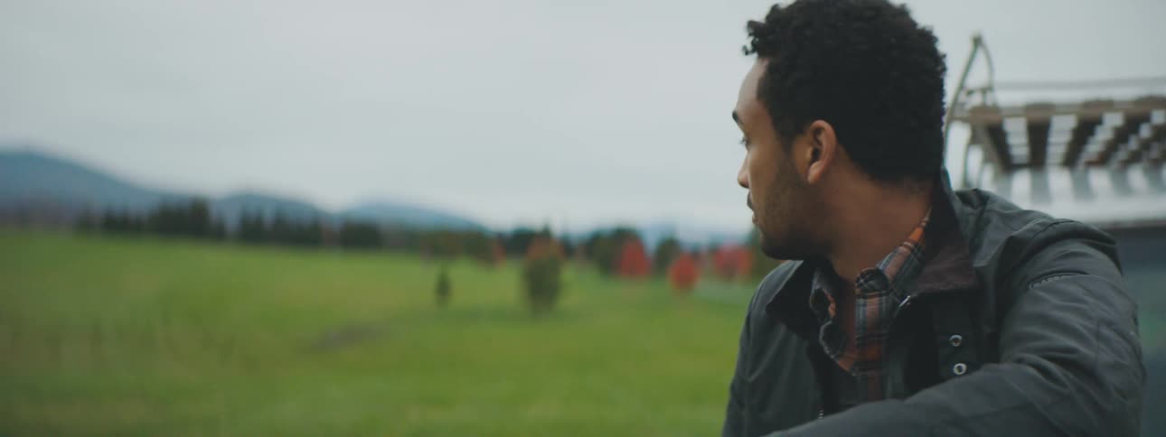 Man sits near vehicle looking at the scenery around him