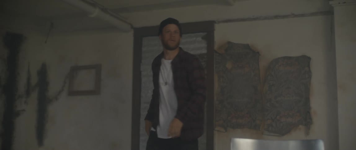 Man locked in a room angrily bangs on a door then turns and walks across the room