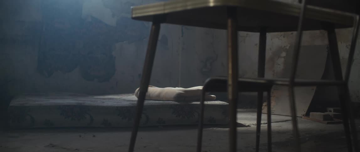 A mattress on the floor of a derelict room during the day