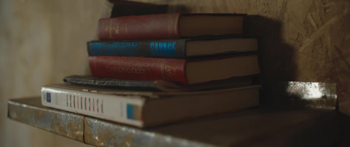 A stack of books sit on a floating shelf