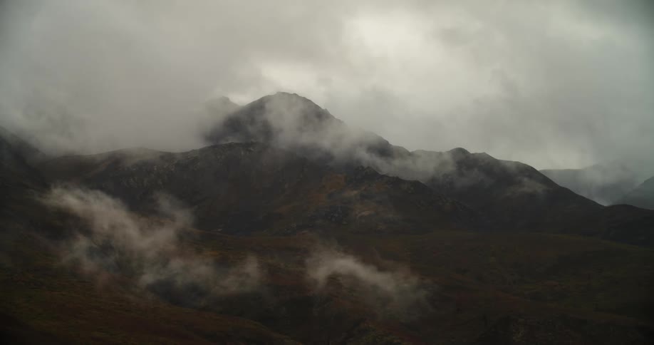 Mist settles over the mountain range under a cloudy sky