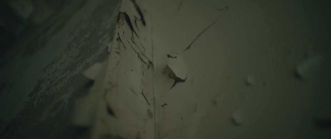 Old paint is cracked and peeling off a wall