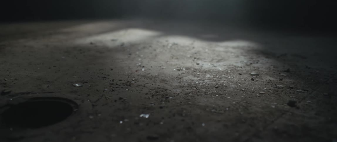 Open drain on the dirty floor of a dimly lit room inside an abandoned building