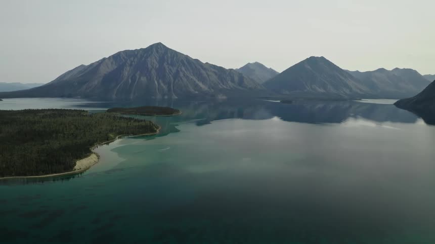 A smooth mountain lake reflects the peaks and trees