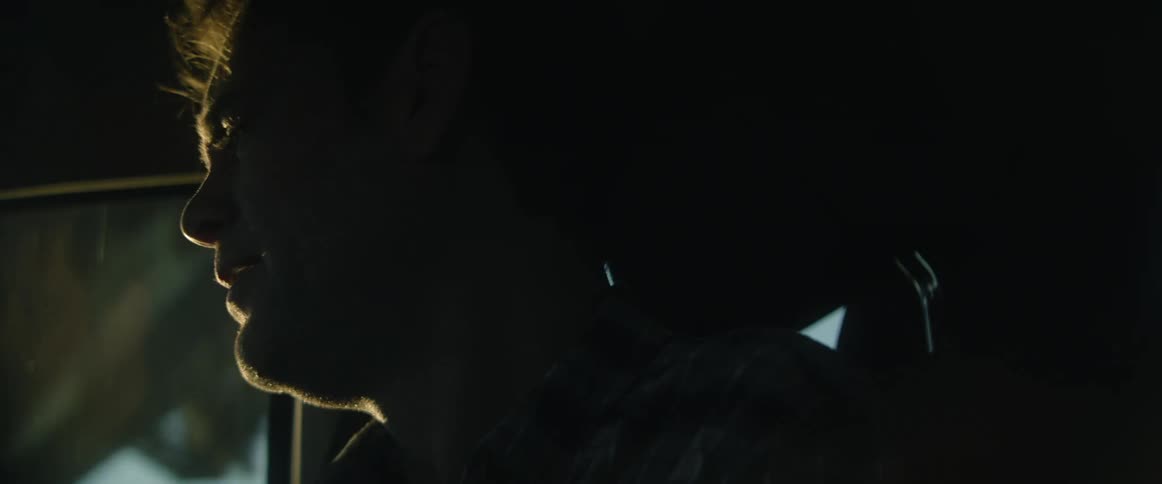Close up of the silhouette of a man sitting on the passenger seat of a car driving under bridges in the morning