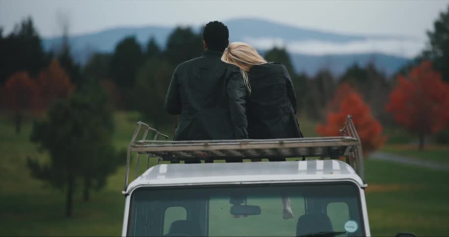 Couple share romantic autumn moment on roof of a car
