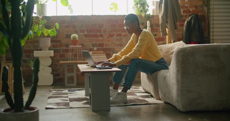 Woman working on a laptop sitting on the couch in the living room