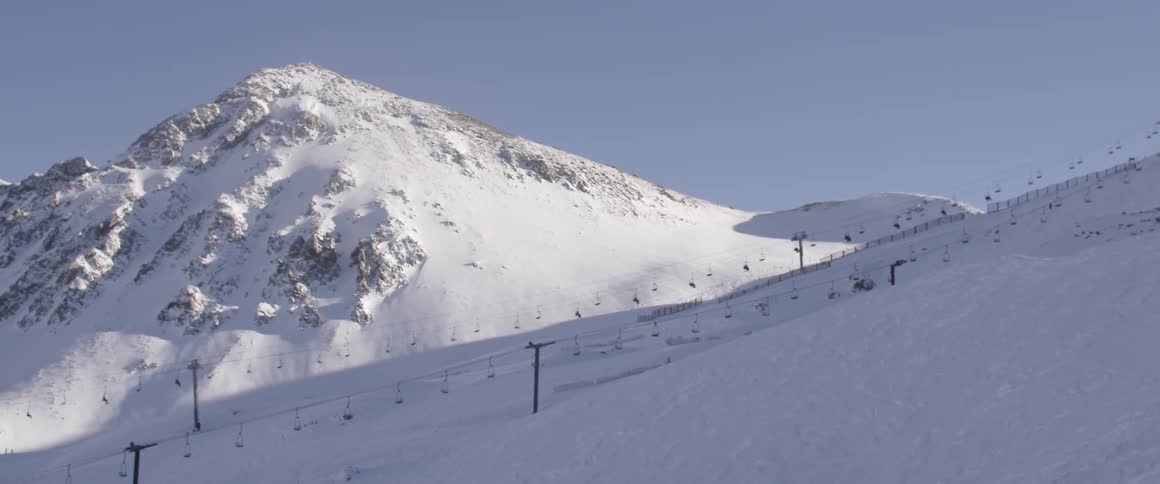 A ski lift near a snow covered mountain