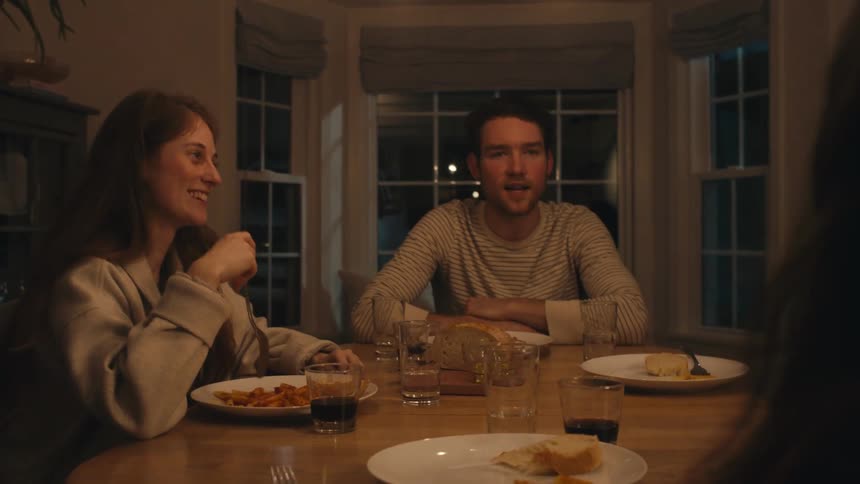 Group of friends or family sitting in the dinning room at home talking while eating at night