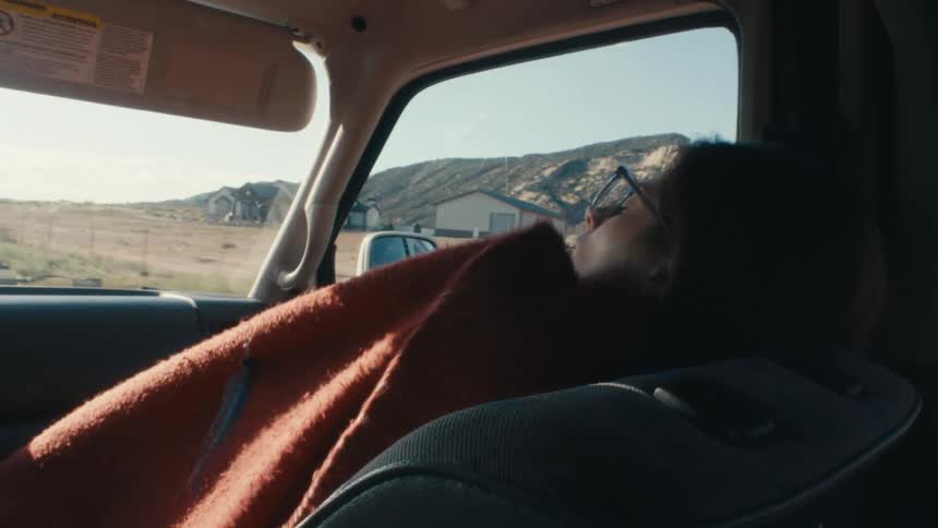 Young woman resting on the passenger seat of a car traveling on the countryside at morning