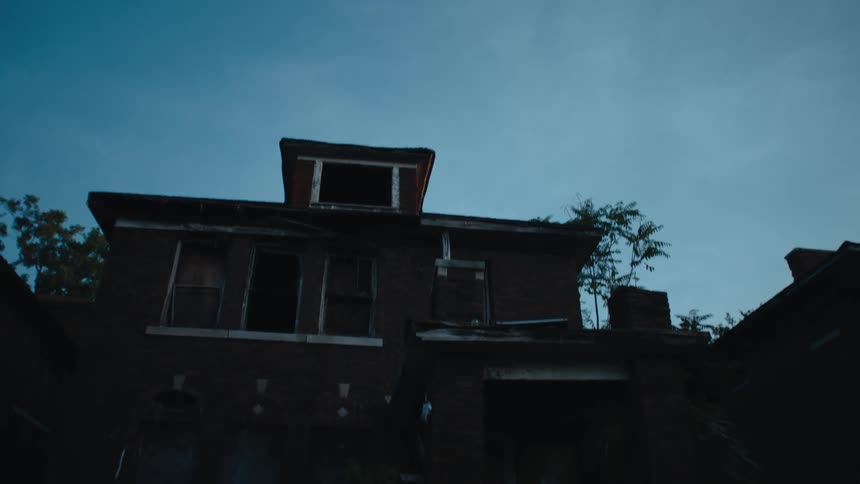 The outside of a home with boarded up and broken windows