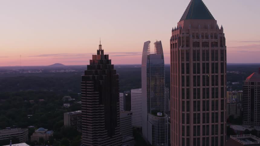 Sun sits on horizon in red sky shining across building under construction in downtown