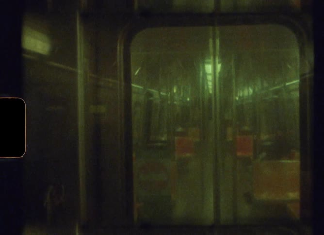 A mass transit train car with ceiling lights on as the train travels at night
