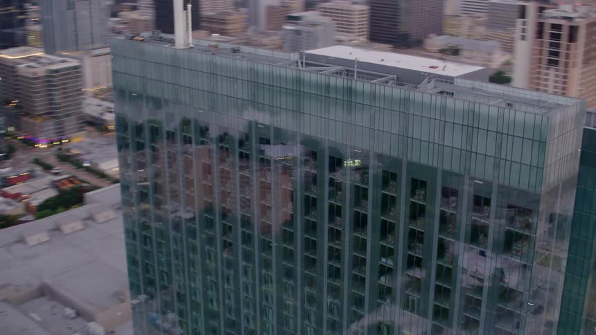Traffic passes by a mirrored skyscraper downtown