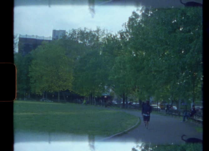 People walking and jogging on a park in the city at morning caught on vintage film