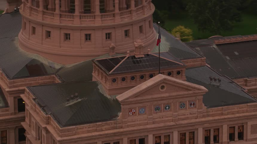 Aerial view of the flag of texas waving over the texas state capitol building