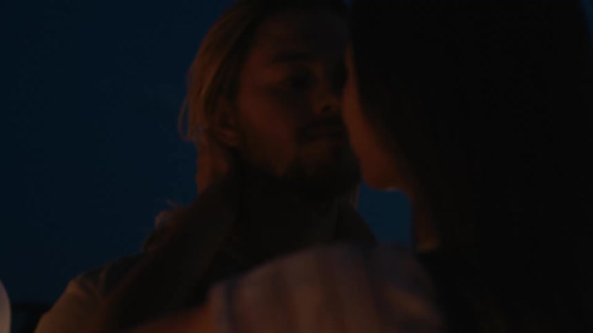 A man and a woman are outside dancing and putting their faces close to each other