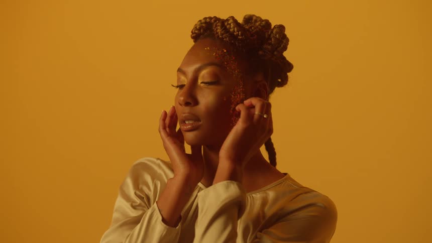 Black model posing during photo shoot against yellow backdrop