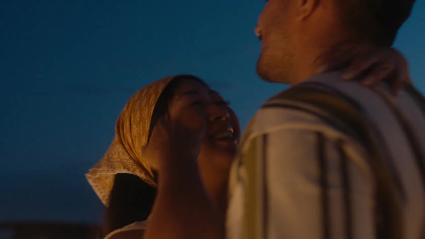 A couple slow dance outside their vehicle at night