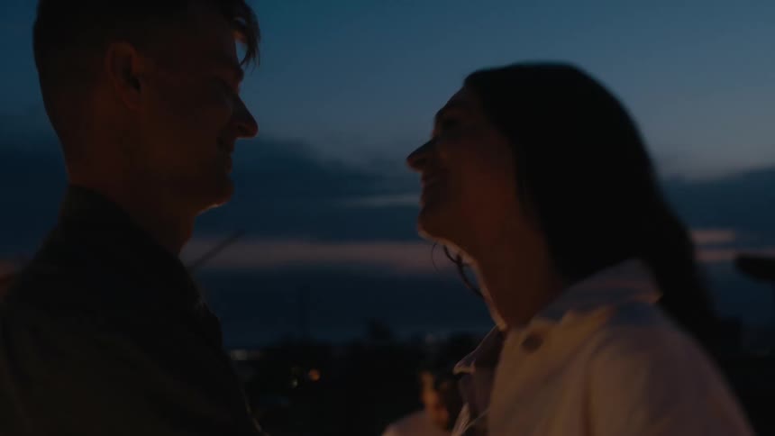 Young happy couple dancing on a party on the rooftop of a building at sunset